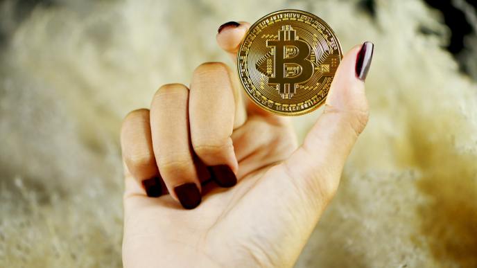 A woman holding a Bitcoin which has become a popular means of transferring funds over the internet, and it is especially beneficial for international payments. (Photo by Executium on Unsplash)