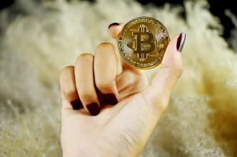 A woman holding a Bitcoin which has become a popular means of transferring funds over the internet, and it is especially beneficial for international payments. (Photo by Executium on Unsplash)