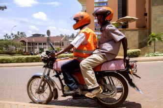 Pioneer moto-taxi ride hailing firm; SafeBoda has been in the business since 2014. A rider is seen wearing a reflective jacket, and helmet carrying an extra one passenger who does have a helmet as well.(Photo Credit: Technology Review)