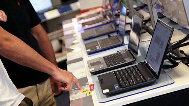 Customers looking at the prices of laptops in a computer store. COURTESY PHOTO