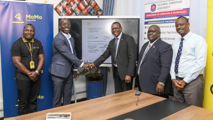 Stephen Mutana; Chief Strategy and Stakeholder Officer at MTN Mobile Money Uganda Ltd (2nd L), shakes hands with David Mugawe; Vice-Chancellor of Uganda Christian University after announcing their partnersips. In the same photo is Nelson Munyanda (extrene left); Manager at MTN Foundation, Vincent Kisenyi (2nd R); Dean of the School of Business and Administration at UCC; and Martin Kabanda (extrene right); Manager in charge of E-learning at MTN Uganda.