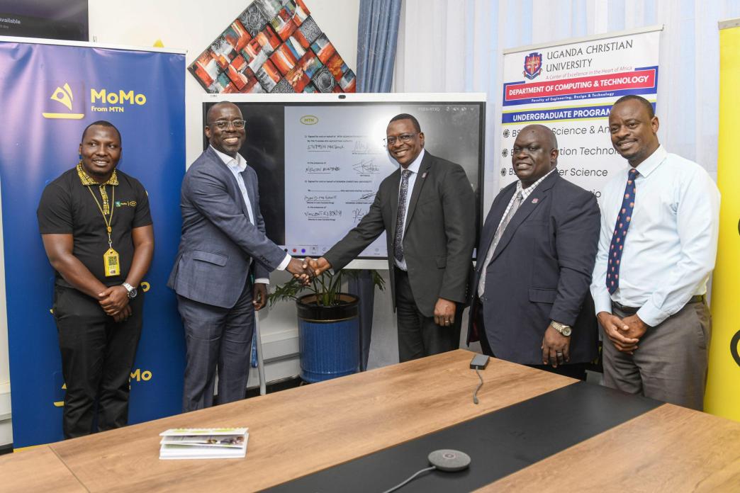 Stephen Mutana; Chief Strategy and Stakeholder Officer at MTN Mobile Money Uganda Ltd (2nd L), shakes hands with David Mugawe; Vice-Chancellor of Uganda Christian University after announcing their partnersips. In the same photo is Nelson Munyanda (extrene left); Manager at MTN Foundation, Vincent Kisenyi (2nd R); Dean of the School of Business and Administration at UCC; and Martin Kabanda (extrene right); Manager in charge of E-learning at MTN Uganda.