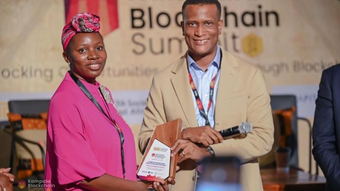 Reginald Tumusiime (right), Chairman of Blockchain Association of Uganda presenting the Excellence in Virtual Assets Research and Policy Framework Award to Sherifah Tumusiime (left), Senior Systems Officer at FIA Uganda. PHOTO: NZE EVE Photography