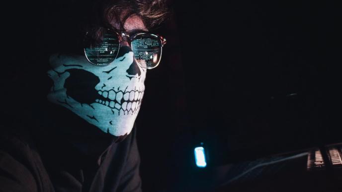 A hacker in a dark room with a covered face typing away at a computer trying to steal personal information or hack into a system is a cybersecurity threat. PHOTO: Nahel Abdul Hadi/Unsplash