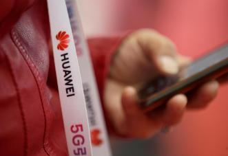 An attendee wears a badge strip with the logo of Huawei and a sign for 5G at the World 5G Exhibition in Beijing, China November 22, 2019. REUTERS/Jason Lee/File Photo UK to use Huawei 5G