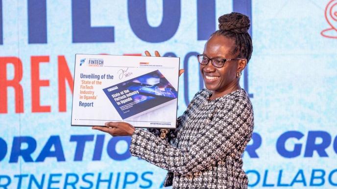 Josephine Olok, FITSPA Uganda board chairperson officially unveiling the 'State of the Fintech Industry in Uganda' report during the 6th annual FITSPA annual fintech conference at the Kampala Sheraton Hotel on Thursday, October 3, 2024. PHOTO: FITSPA