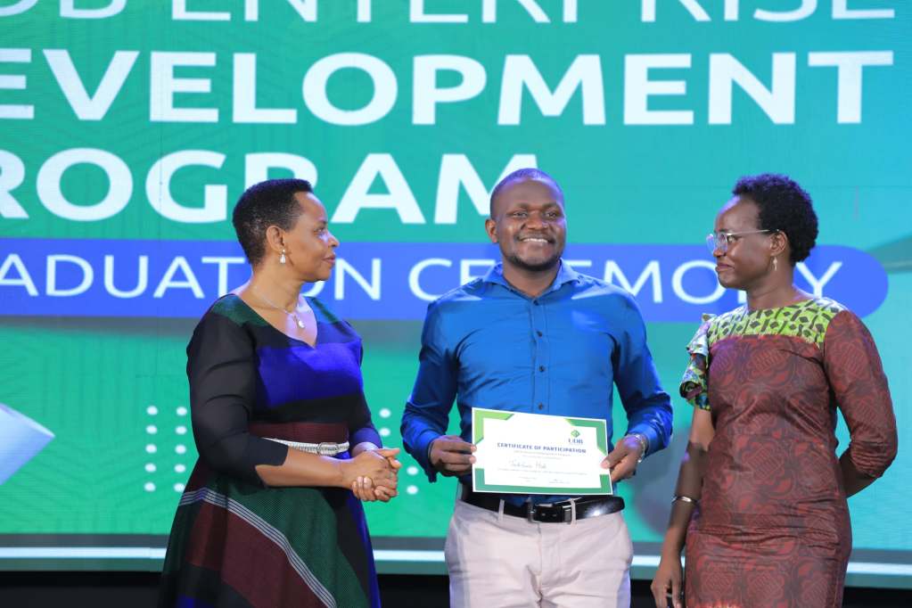 Keneth Twesigye (centre) excited after receiving certificate from UDB after his completion of a three months Incubation Program. Courtesy Photo/FILE PHOTO