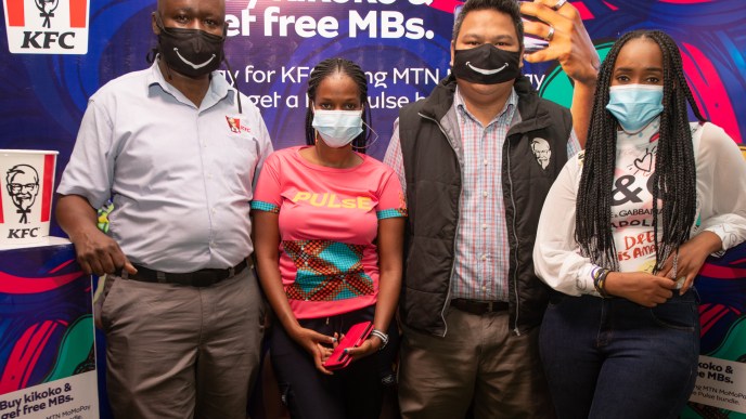 Hellen Kirungi (2 from left) the MTN Youth Segment Manager and MTN Pulse ambassador, Faiza (far right) pose for a group photo with the Kampala Boulevard KFC outlet staff at the partnership launch.