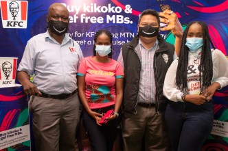 Hellen Kirungi (2 from left) the MTN Youth Segment Manager and MTN Pulse ambassador, Faiza (far right) pose for a group photo with the Kampala Boulevard KFC outlet staff at the partnership launch.