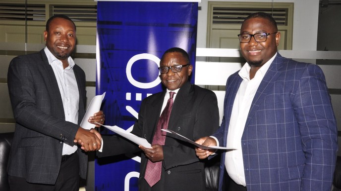 (Left –Right) Raxio's General Manager James Byaruhanga, Paul Nalikka; Director at Hamilton Telecom, flanked by Ahura Vianne Allan the CFO exchange agreements at Raxio's Rwenzori Towers, offices in Nakasero, Kampala.