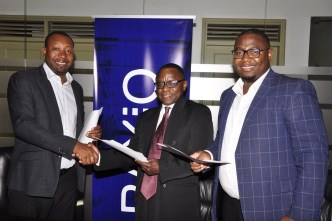 (Left –Right) Raxio's General Manager James Byaruhanga, Paul Nalikka; Director at Hamilton Telecom, flanked by Ahura Vianne Allan the CFO exchange agreements at Raxio's Rwenzori Towers, offices in Nakasero, Kampala.