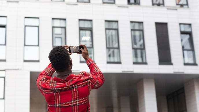 Pictured a young male adult taking pictures of a building. PHOTO: Freepik