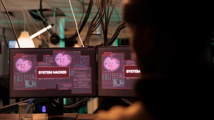 A hacker watches a system hacked alert message appear on a computer screen. PHOTO: DCStudio / via Freepik