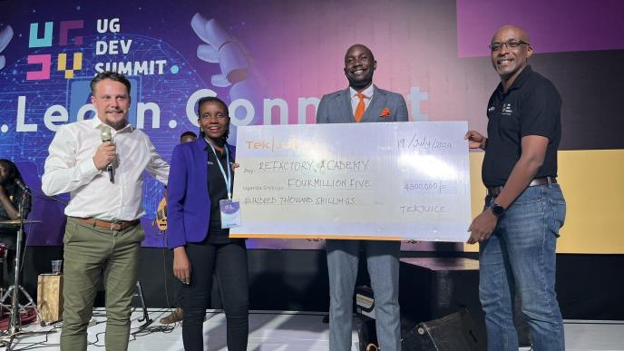 Tekjuice CEO, Jason Hathaway (extreme left), and Deputy CEO, Isaac Odongo (2nd from right) handover a dummy cheque of UGX4.5 million to Refactory Academy's Executive Director Michael Niyitegeka at the end of the Uganda Developers Summit. PHOTO: Refactory