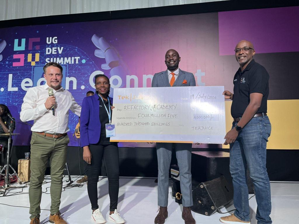 Tekjuice CEO, Jason Hathaway (extreme left), and Deputy CEO, Isaac Odongo (2nd from right) handover a dummy cheque of UGX4.5 million to Refactory Academy's Executive Director Michael Niyitegeka at the end of the Uganda Developers Summit. PHOTO: Refactory