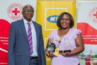 MTN Uganda's General Manager, Ms. Enid Edroma (R) poses with the Humanitarian Award received from the Uganda Red Cross Society Secretary-General, Mr. Robert Kwesiga (L).