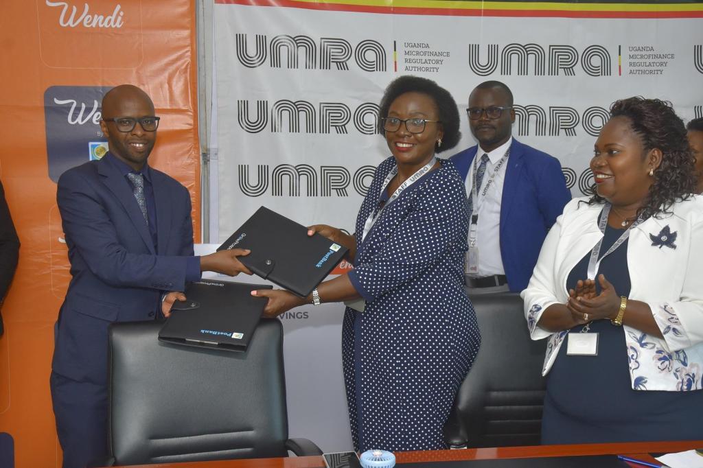 Andrew Kabeera (left); PostBank Uganda Executive Director and Edith Tusuubira (right); Executive Director of UMRA exchange MoUs that initiate a collaboration aimed at digitizing the operations of tier IV Microfinance Institutions. Courtesy Photo