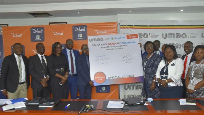 Andrew Kabeera; PostBank Uganda Executive Director (5th L) and Edith Tusuubira (3rd R Front; Executive Director of UMRA, joined by other officials from PostBank Uganda and UMRA pose for a photo after the signing of an MoU to initiate a collaboration aimed at digitising the operations of tier IV Microfinance Institutions. Courtesy Photo