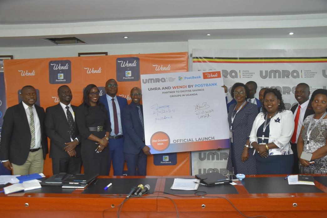 Andrew Kabeera; PostBank Uganda Executive Director (5th L) and Edith Tusuubira (3rd R Front; Executive Director of UMRA, joined by other officials from PostBank Uganda and UMRA pose for a photo after the signing of an MoU to initiate a collaboration aimed at digitising the operations of tier IV Microfinance Institutions. Courtesy Photo